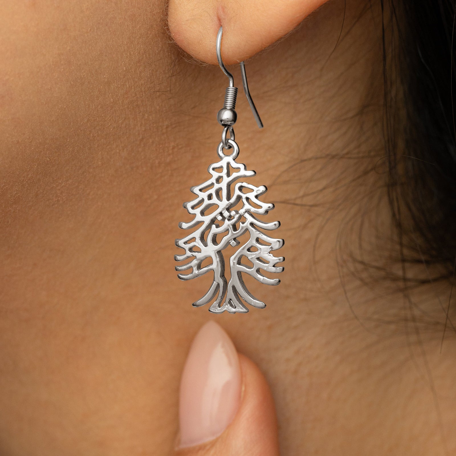 Close up photo of the dangling silver earring showing its intricate design.