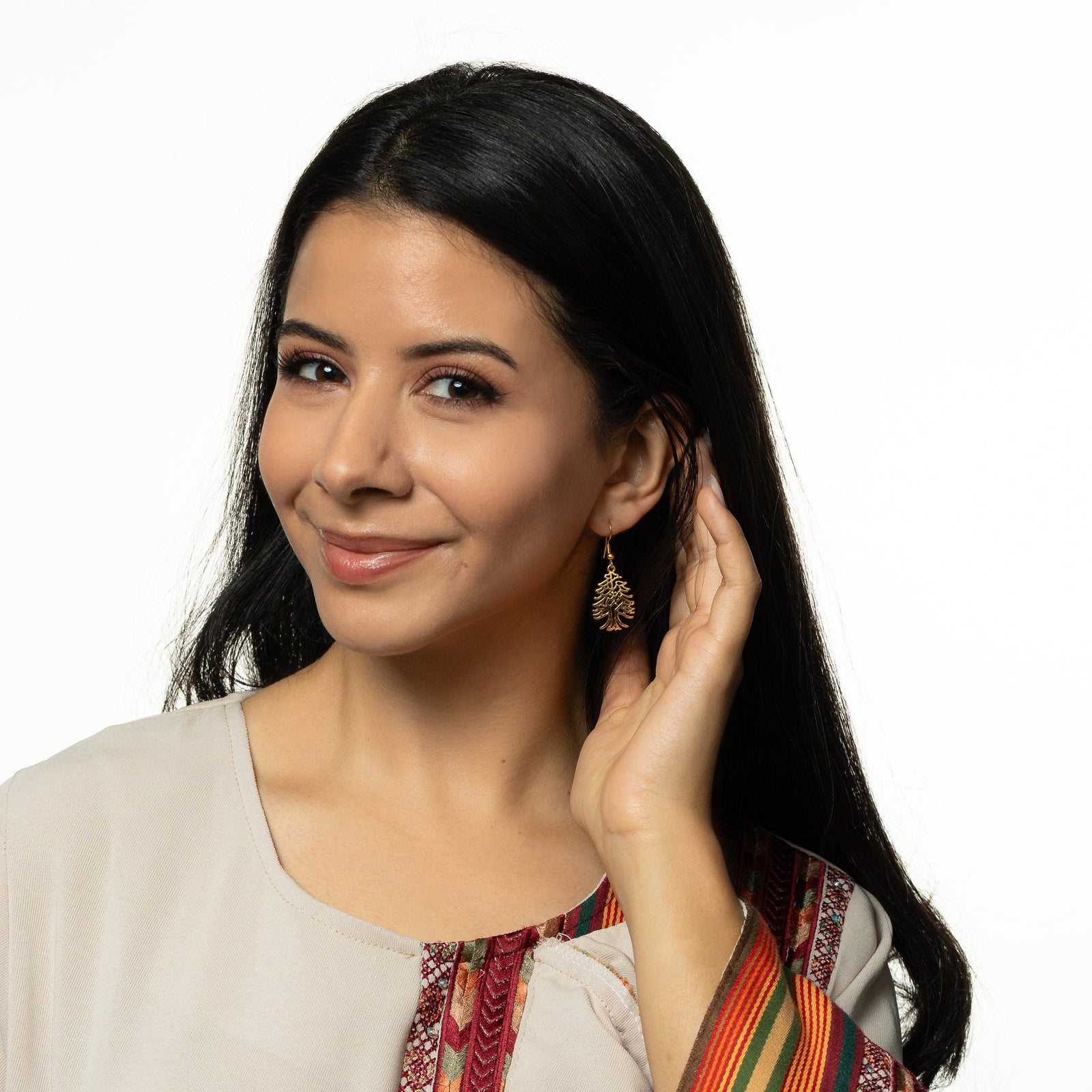 Model holds their hair away from their left ear showing the dangling Freedom is the Soul Cedar gold earring.