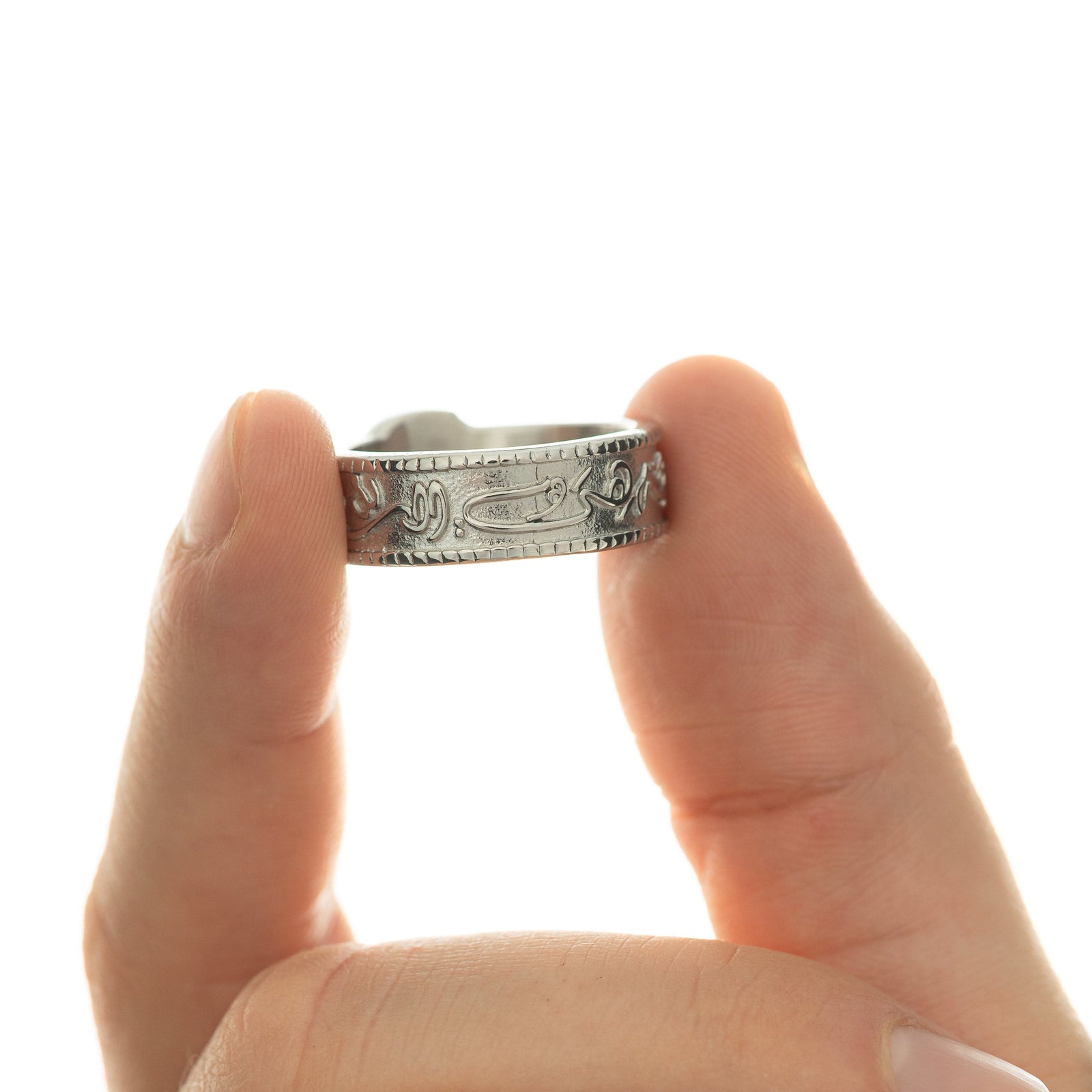 Model holds the silver ring between their thumb and index finger to show the design of the ring's band.