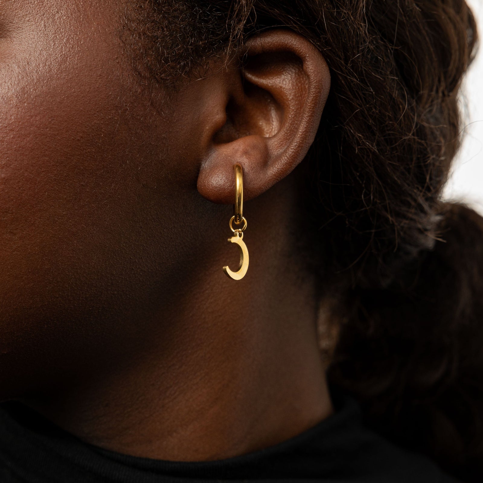 Close up of the Galaxy Hoop Earring with crescent moon charm as worn by the model on their left ear.