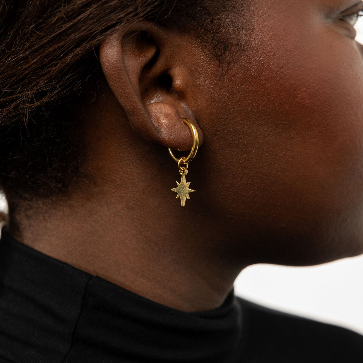 Close up of the Galaxy Hoop Earring with star charm as worn by the model on their right ear.