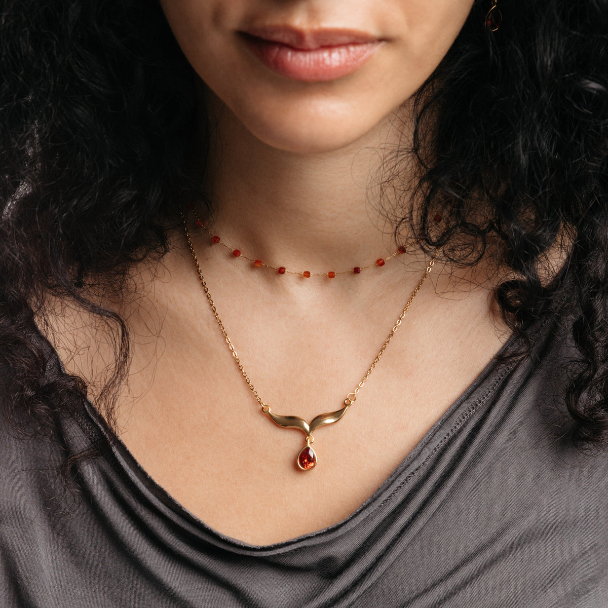 Model styled in 18k gold-plated Nominal jewelry featuring the Garnet Stone Keffiyeh Necklace layered with the Essential Red Agate Micro Chain.