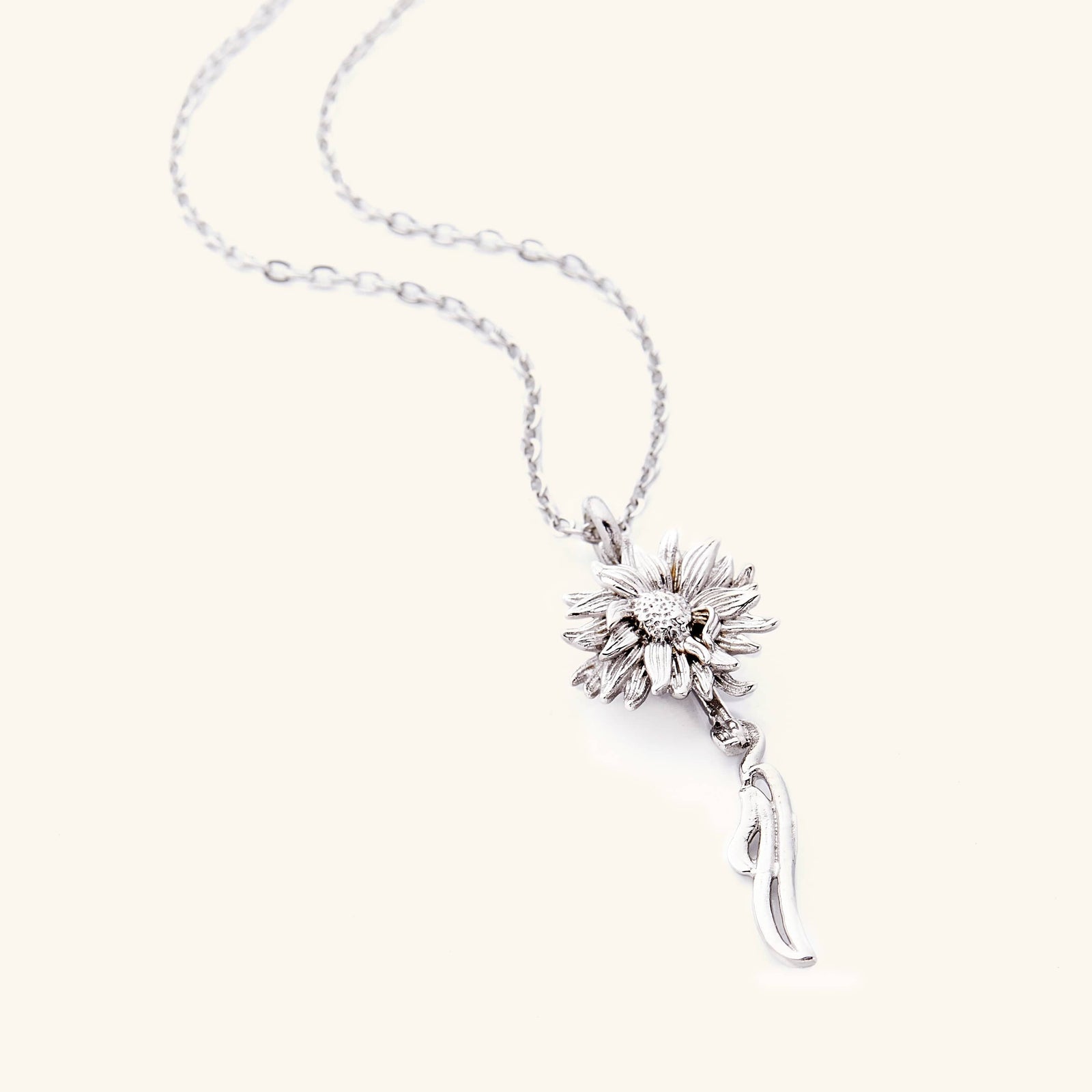 A silver necklace that features a sunflower shaped pendant with Arabic word for ‘happiness’, curving in calligraphy out of the stem of the flower