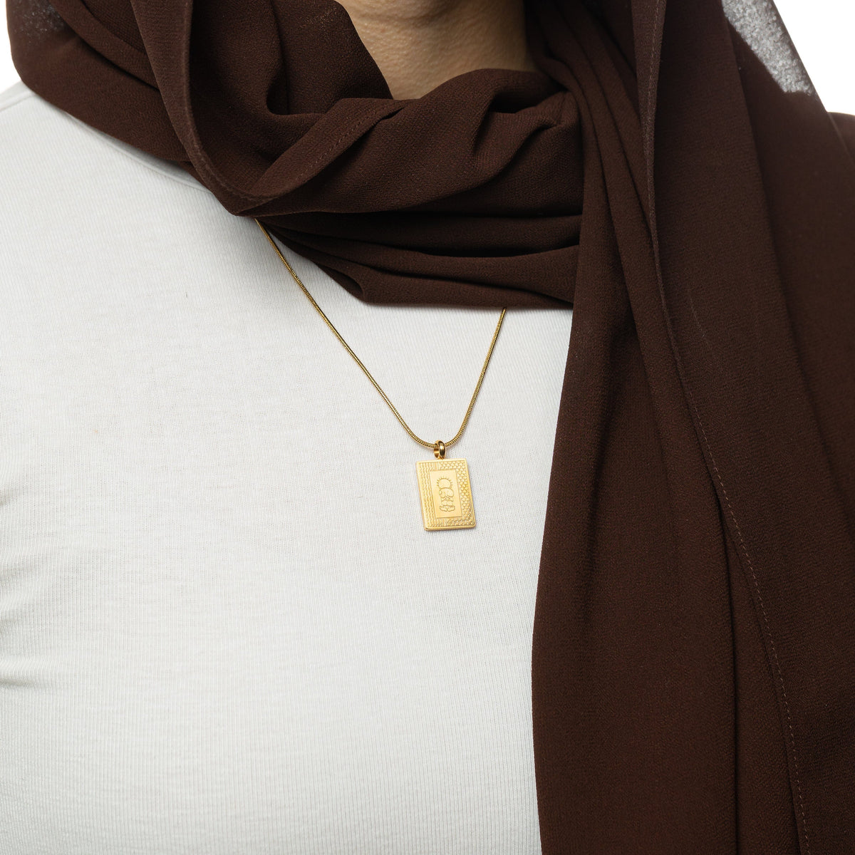 Gold Handala Necklace worn by a woman wearing a brown hijab and white shirt