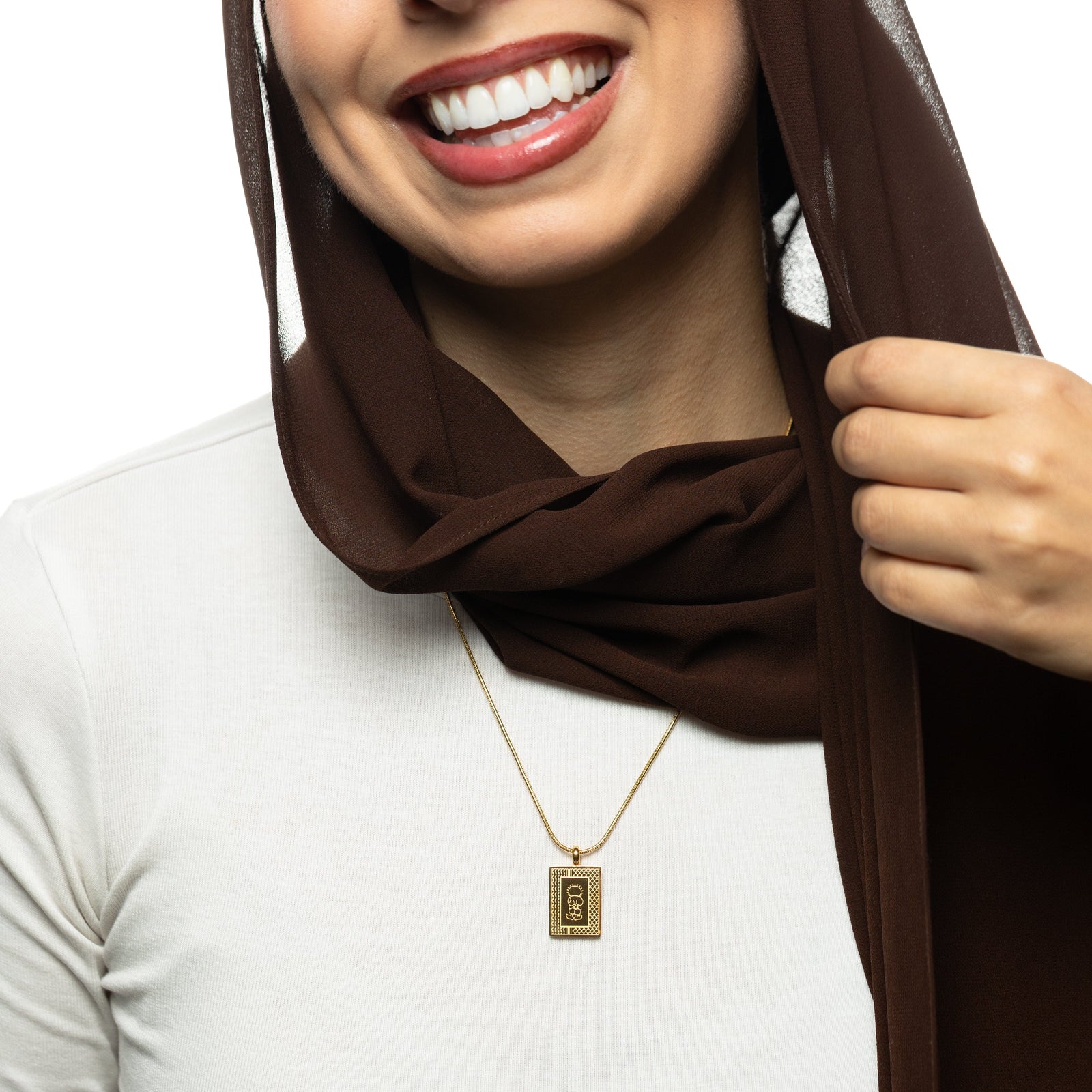 Woman wearing a brown hijab, white shirt, and gold Handala Necklace