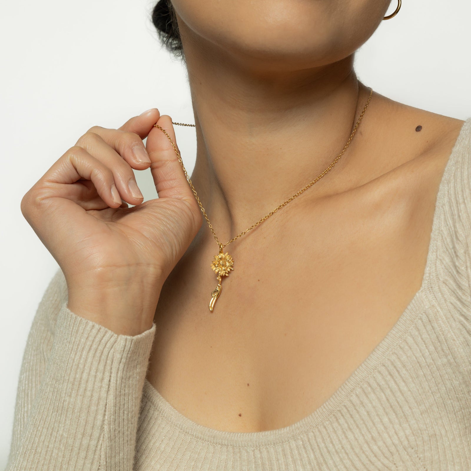 Photo of the model lifting the gold chain of their necklace.