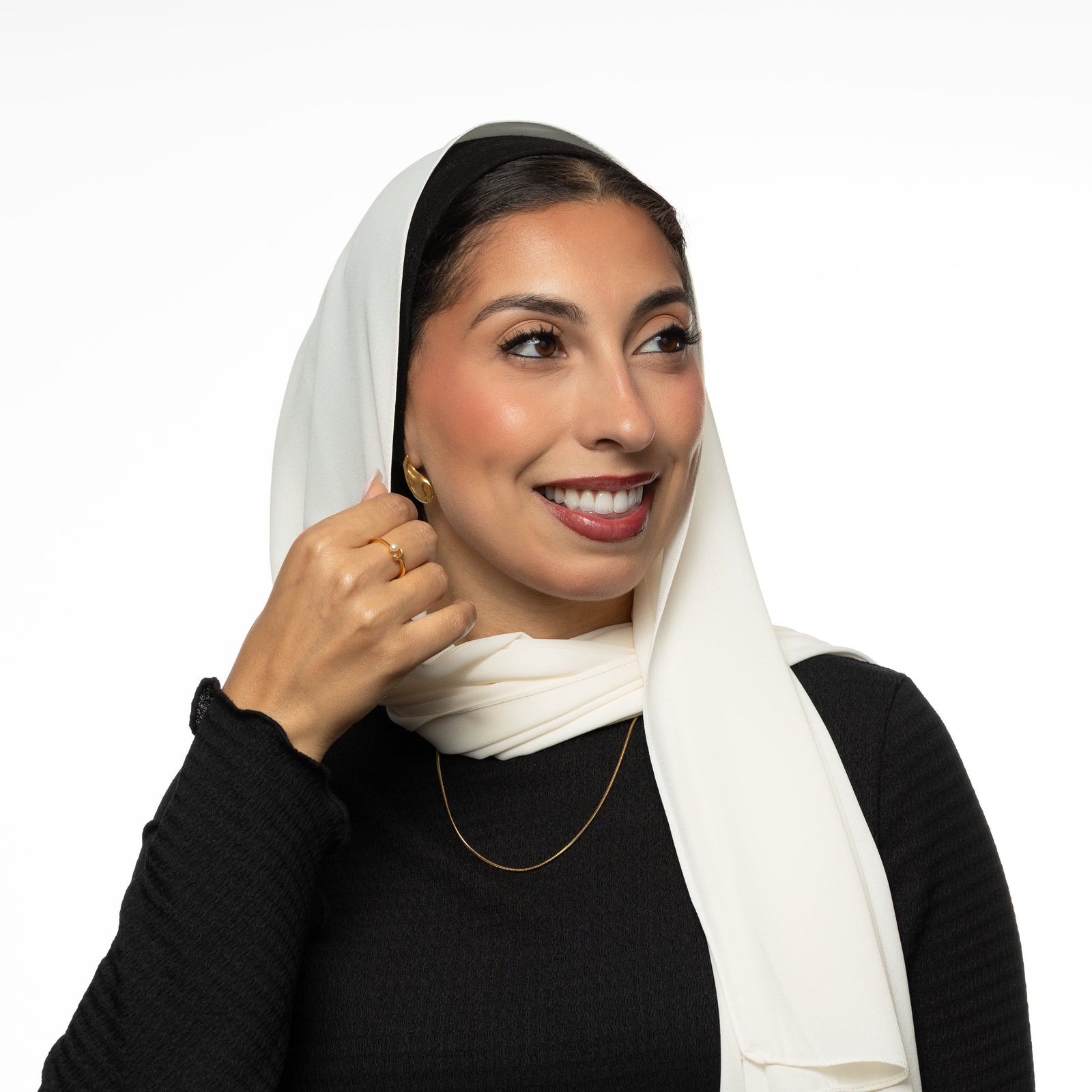 Woman wearing a white hijab, black top, and a harmony necklace.
