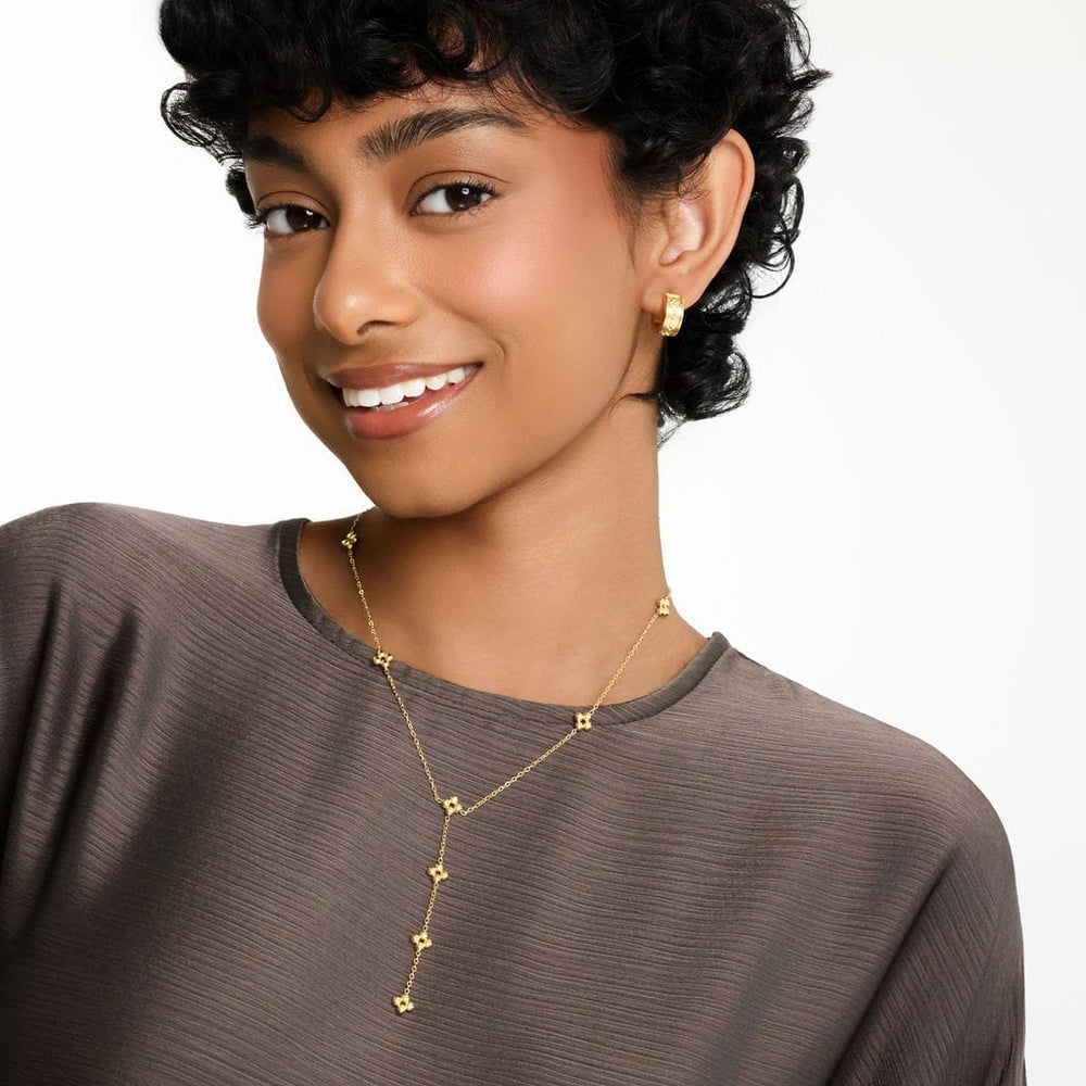 Photo of the model smiling to the camera. The model is wearing the gold Henna Lariat Necklace