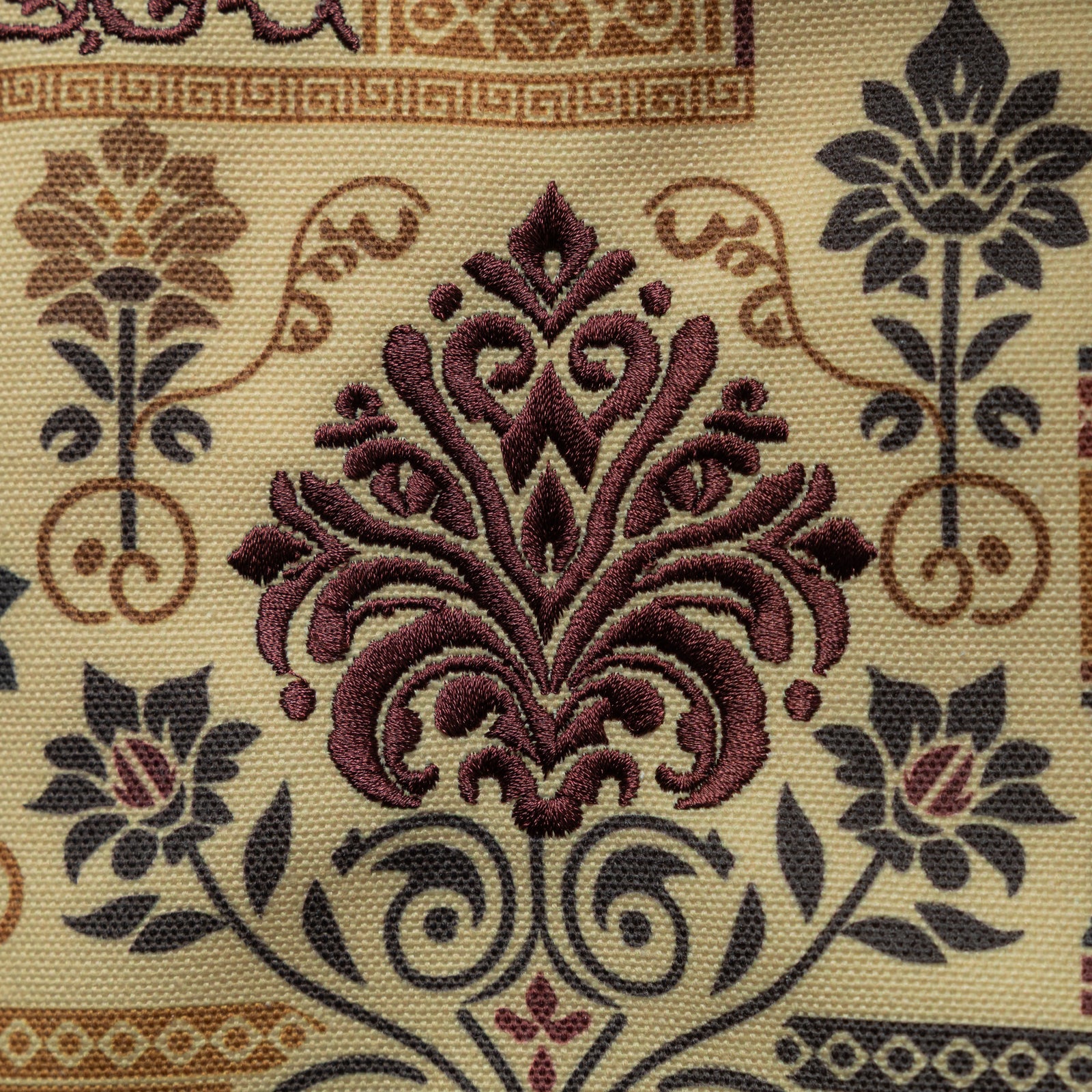 Close-up of the maroon embroidered motif on the heritage tote bag, showing raised textured stitching and detailed patterning.