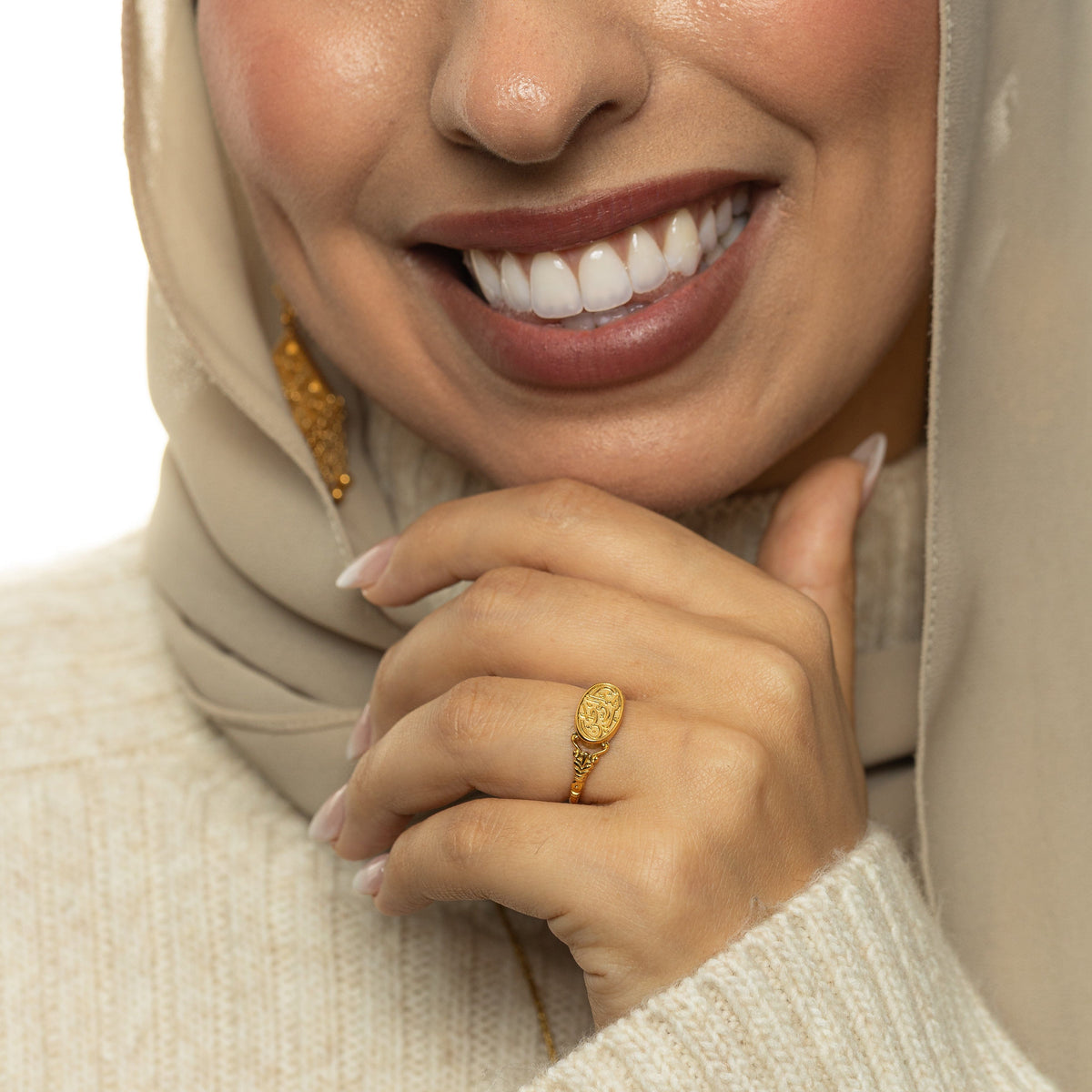 Woman wearing the gold Homeland Ring with Arabic calligraphy on the oval face in a close-up hand shot.