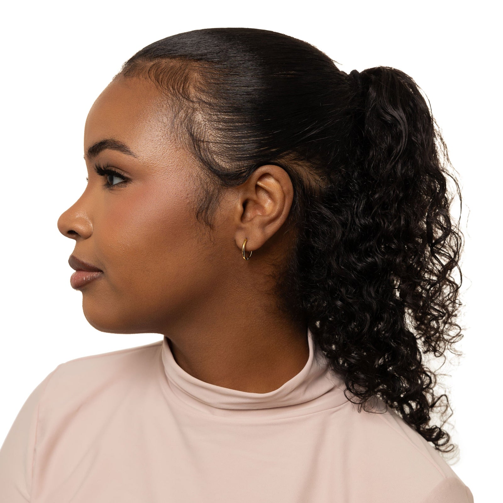 Photo of the model's left side profile. The model is wearing the silver Huggie Essential Hoops | 12mm on their left ear.