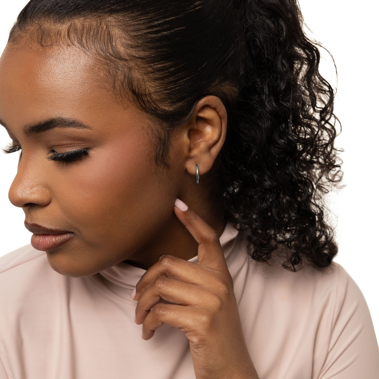 The silver Huggie Essential Hoops | 12mm as worn by the model.