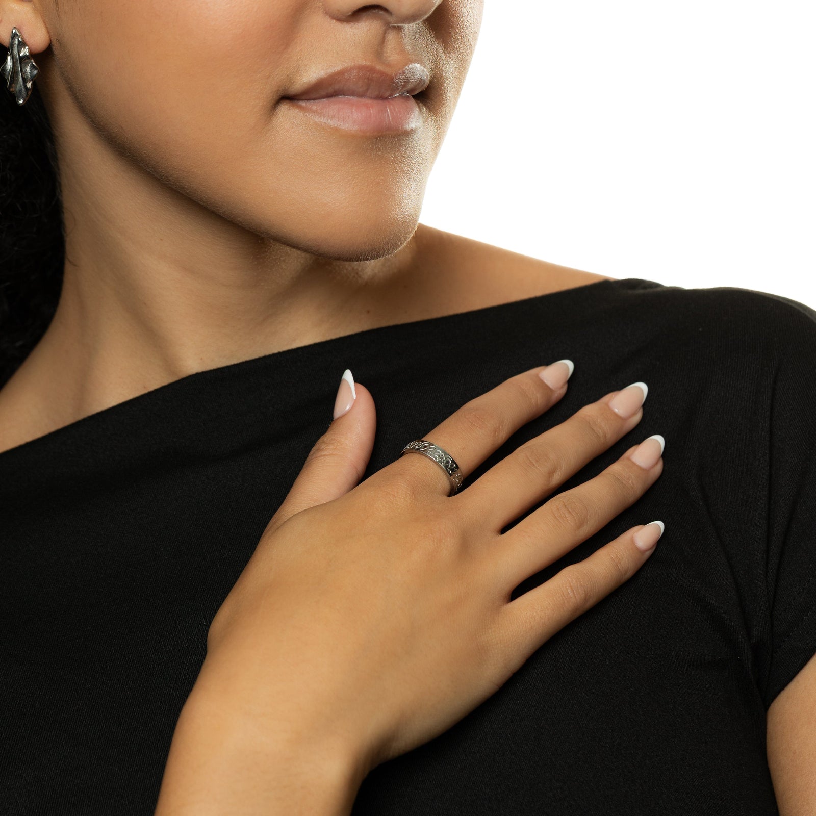 Photo of the model resting their right hand on their chest, the model is wearing the silver “Hurriya” | Freedom Ring on their right index finger