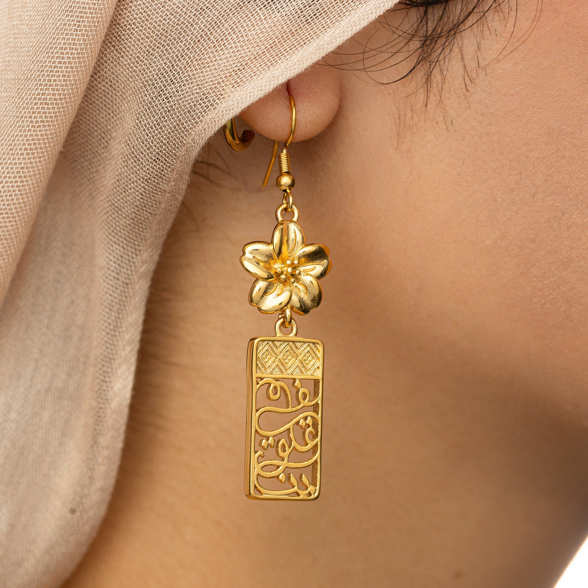 Close up of the In Our Hearts Damascus Earrings as the model wears it on their right ear.