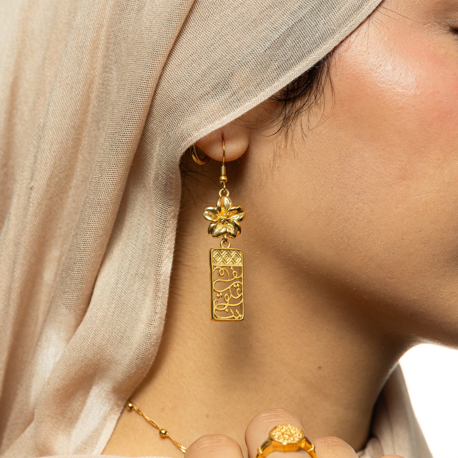 Close up the gold In Our Hearts Damascus Earrings as the model wears it on their ear.
