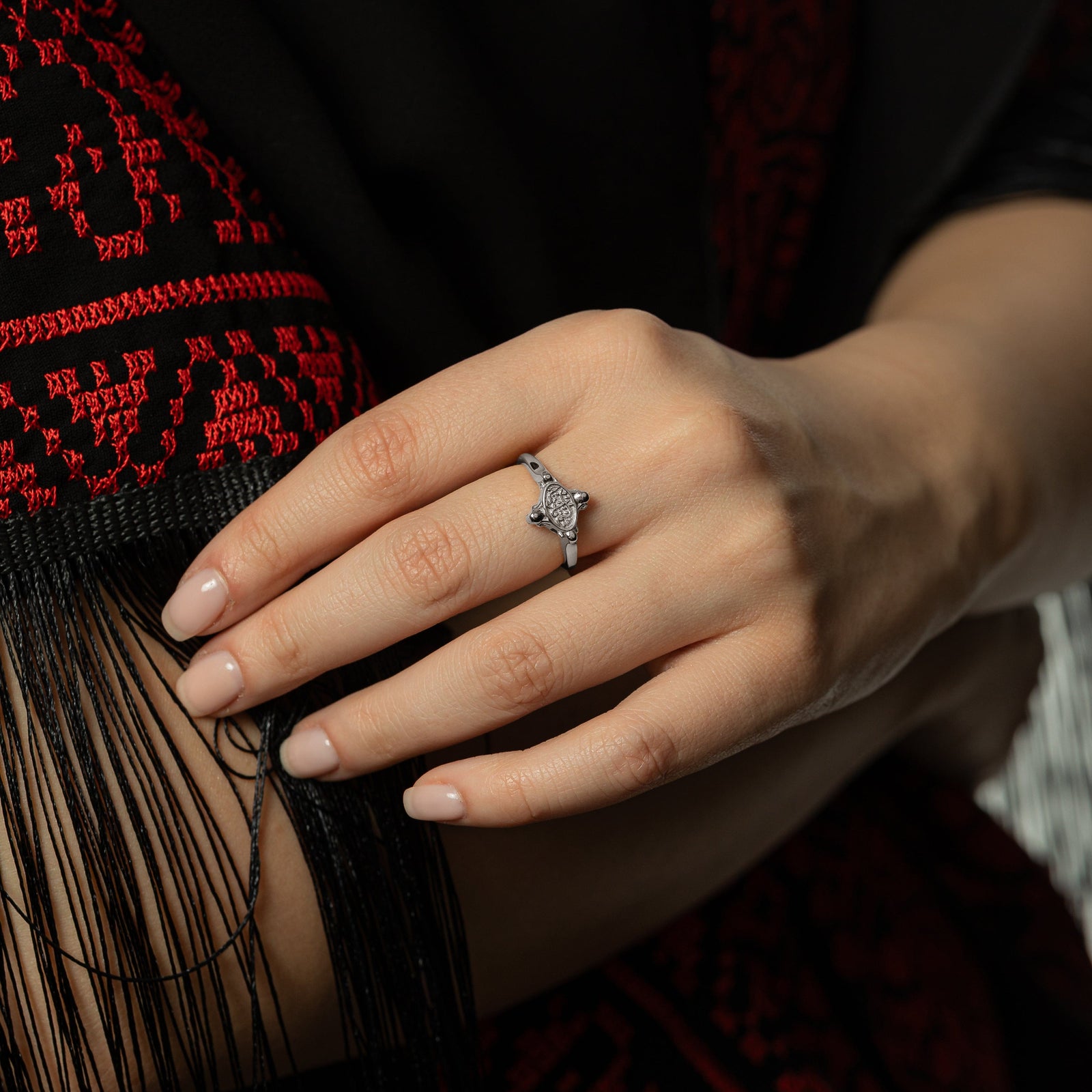 Model touching the tassels of fabric. Model is wearing the silver In Our Hearts Vintage ring.