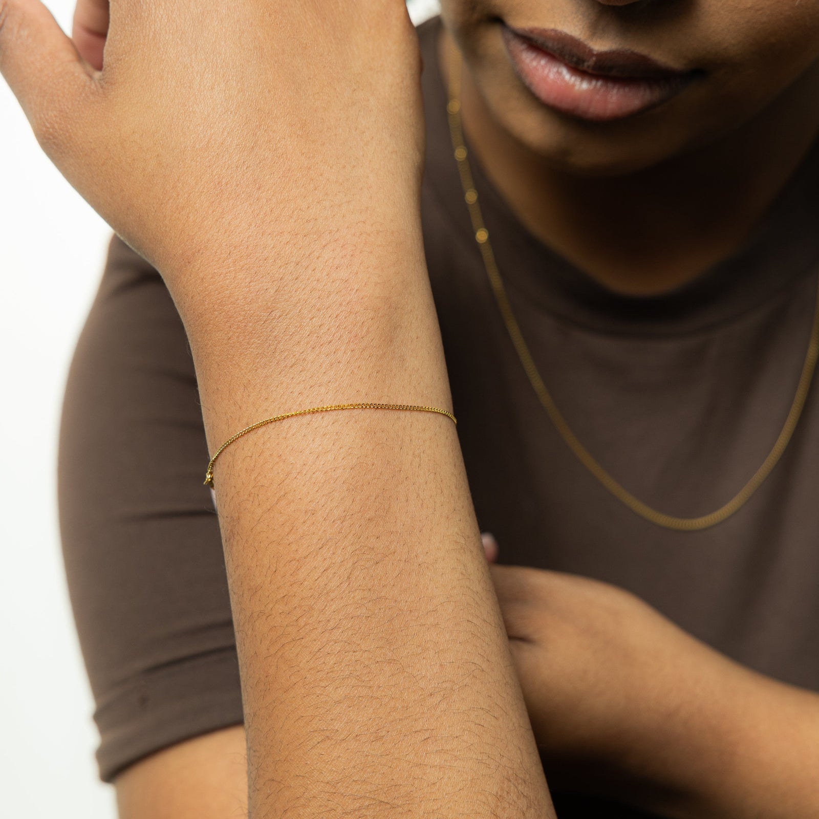 The gold Micro Curb Bracelet as worn by the model on their right wrist.