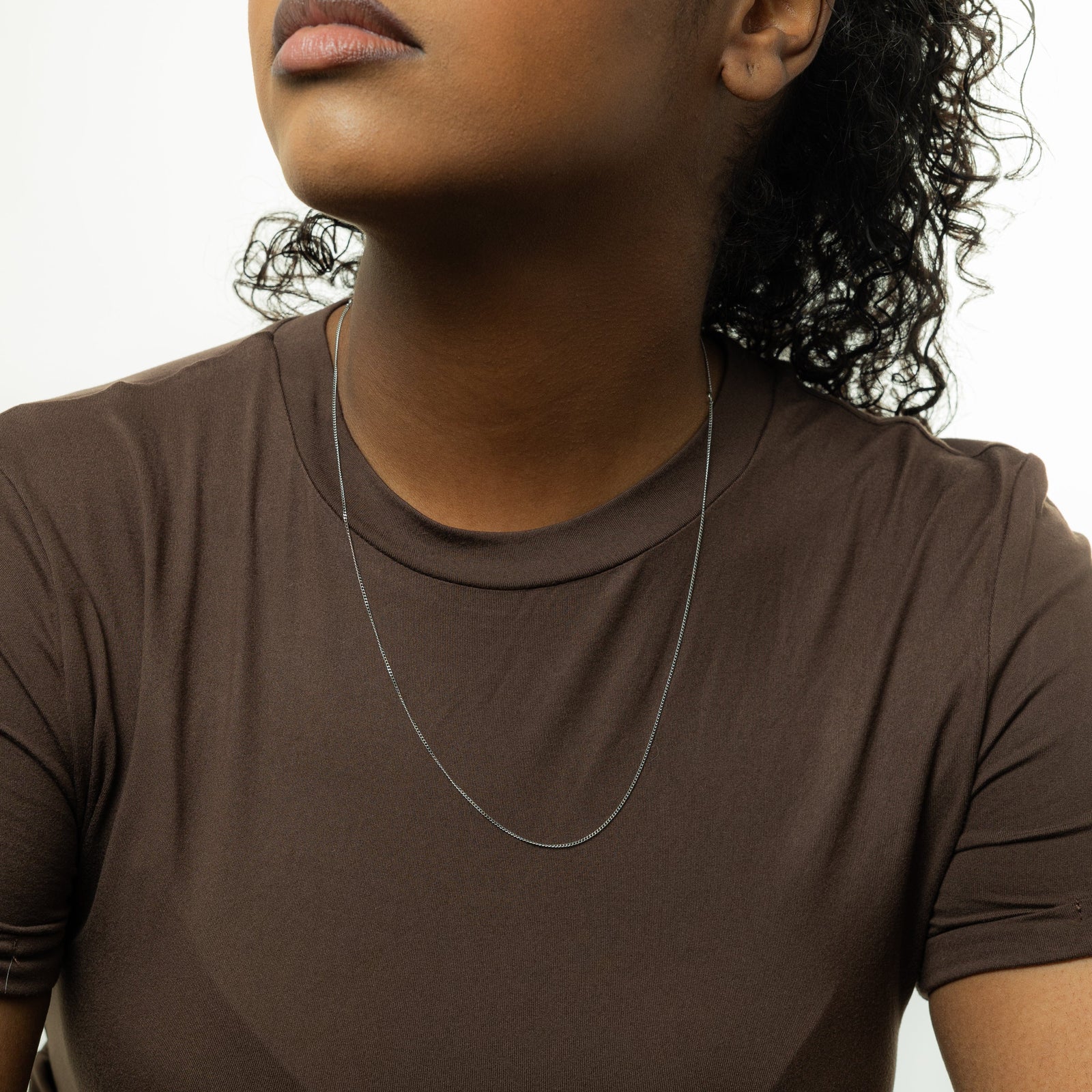 Close up of the silver Micro Curb Chain as worn by the model.