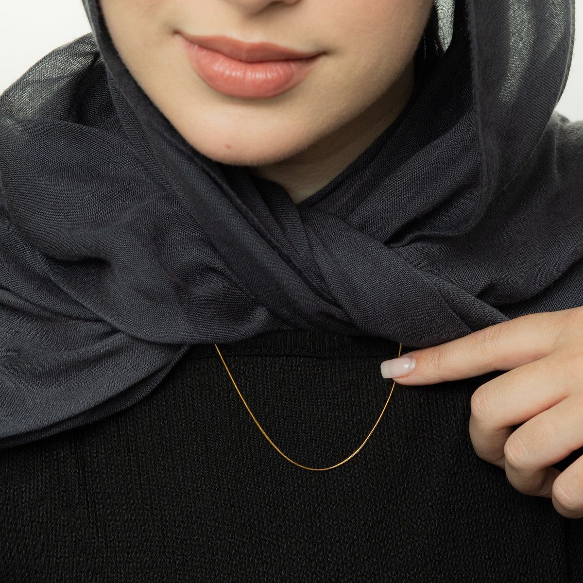 Close up of the gold Micro Harmony Chain as worn by the model.
