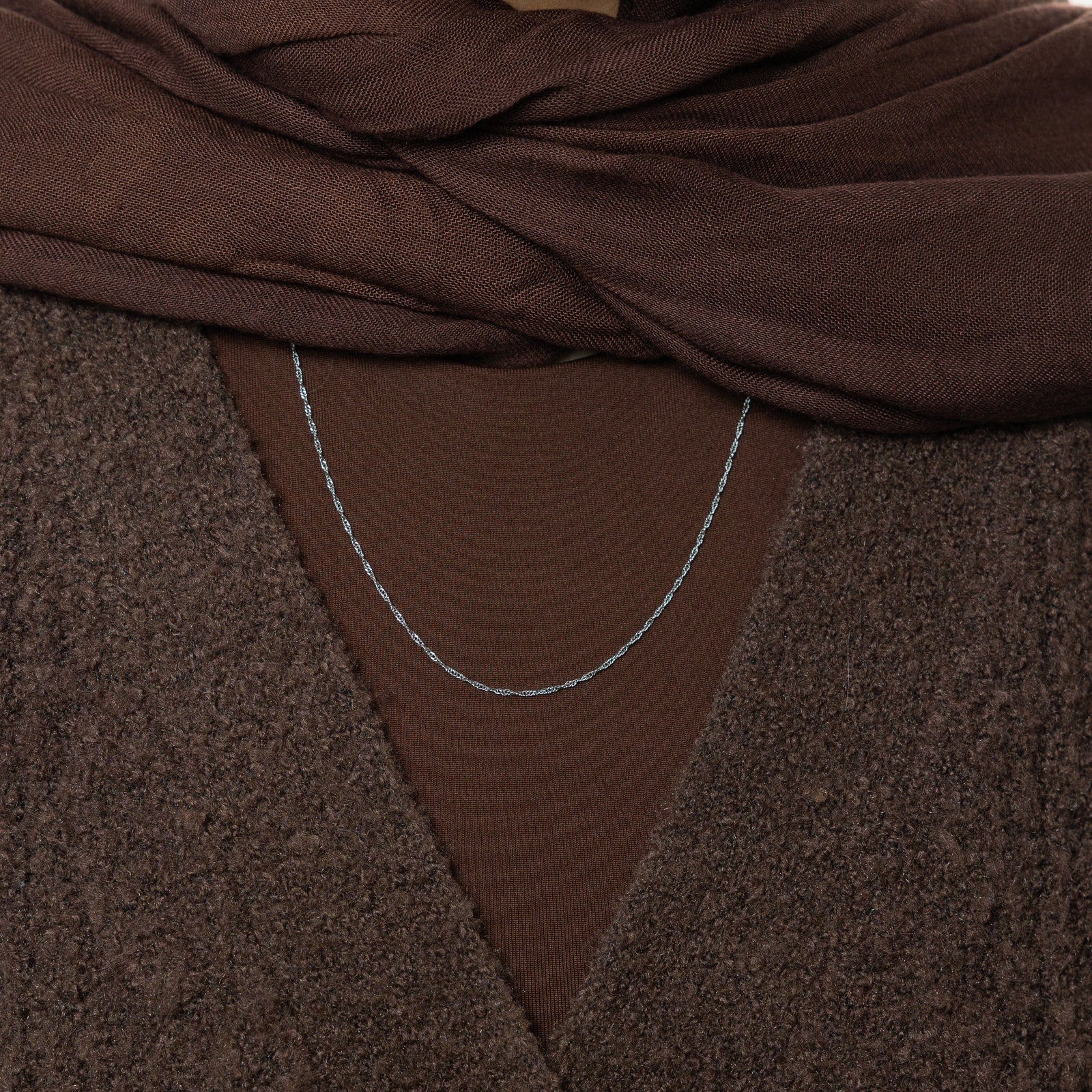 Close up of the silver Micro Twisted Chain against the dark fabric of the model's clothing.