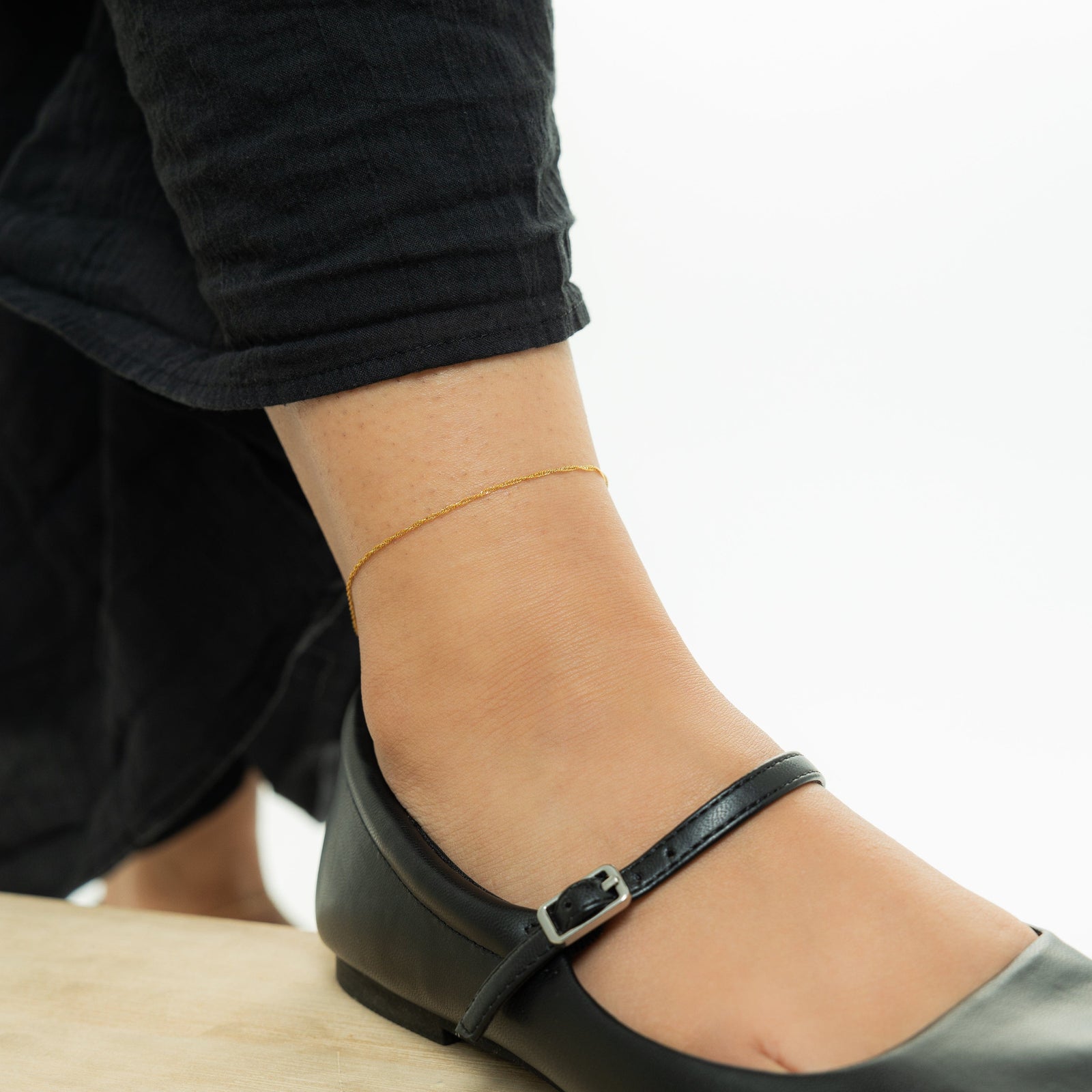 Photo of the model's right foot. They are wearing the gold Micro Twisted Anklet.