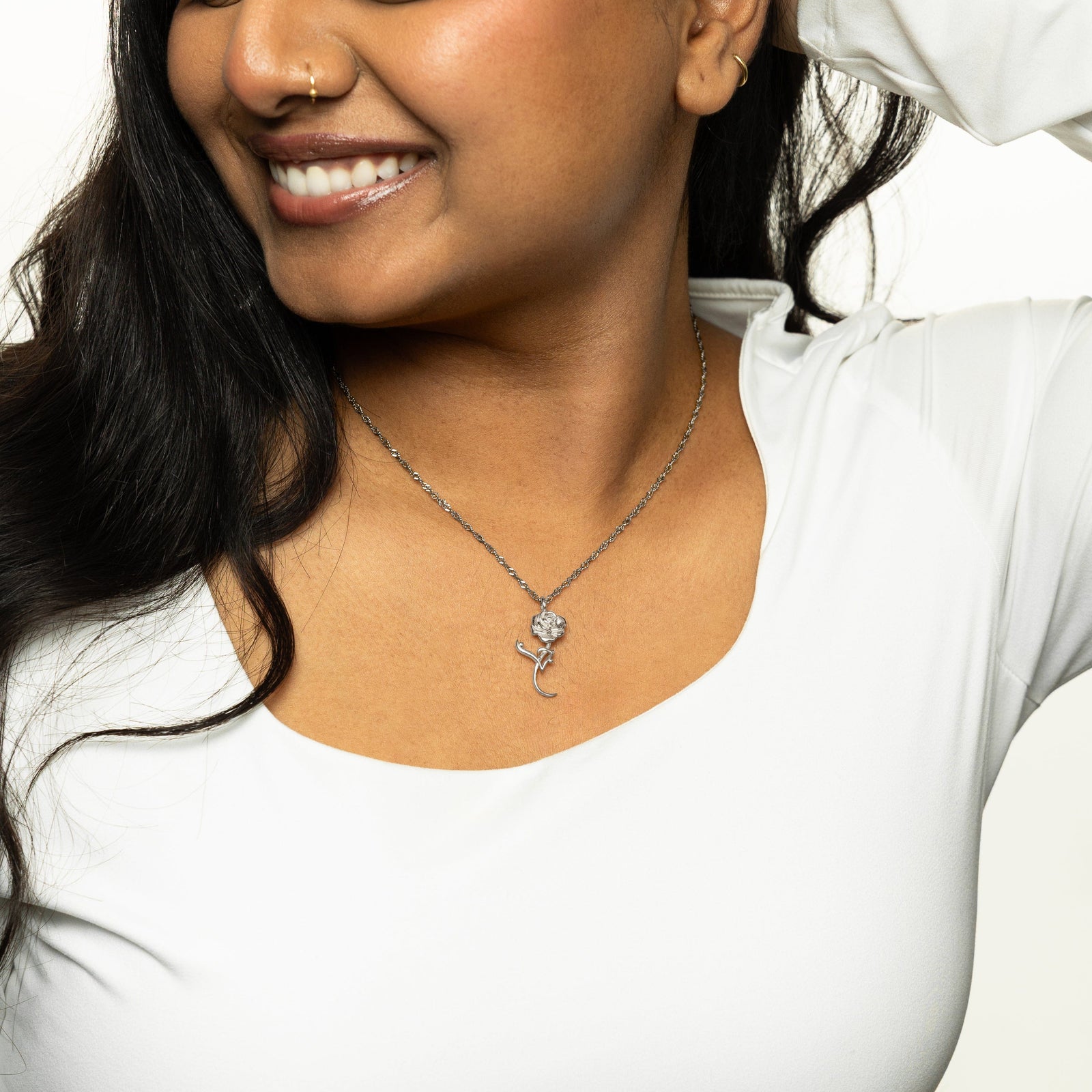 Woman wearing a silver jaan rose necklace, styled with a white top.