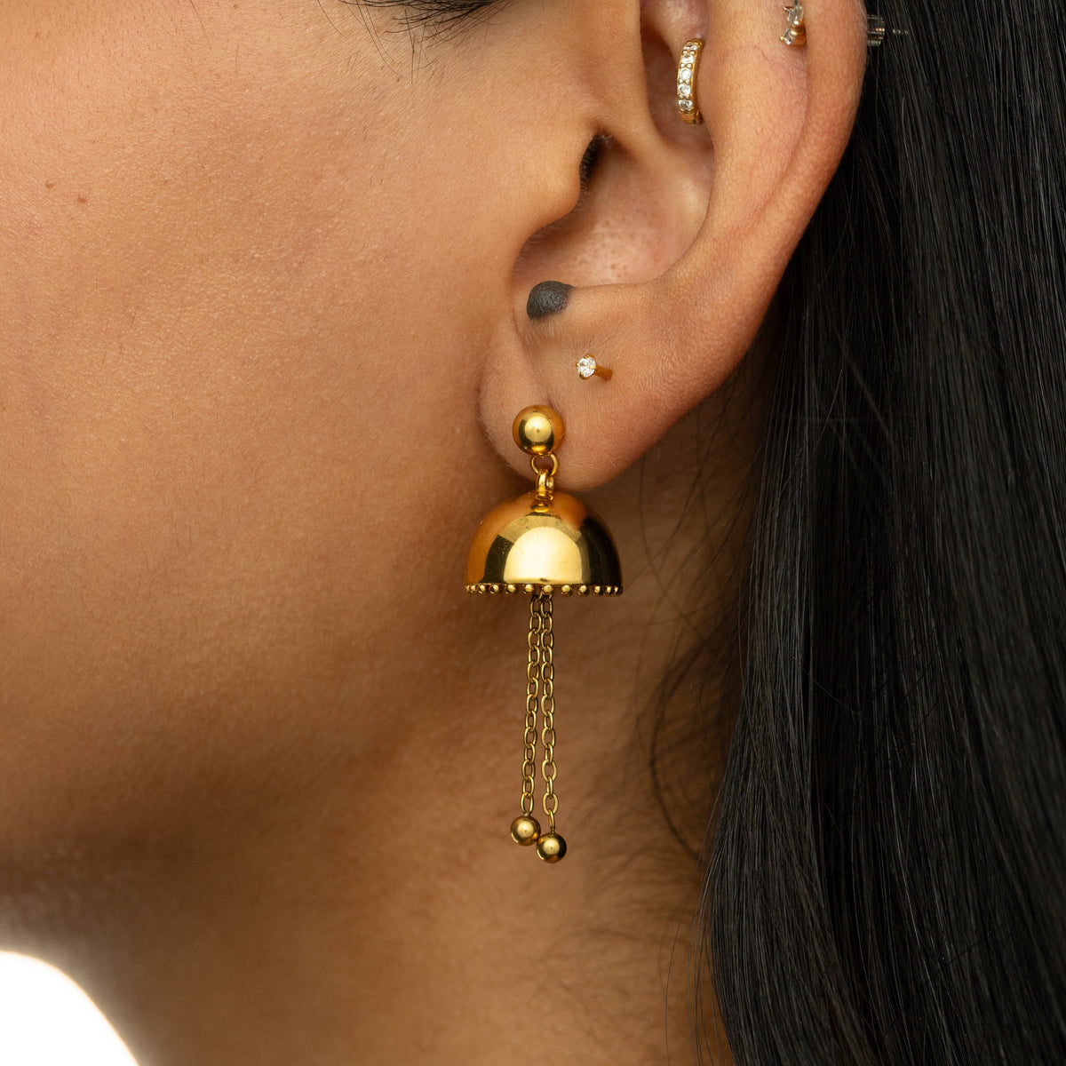 Gold Jhumka Earring with dome top and two dangling chain drops, styled on ear.