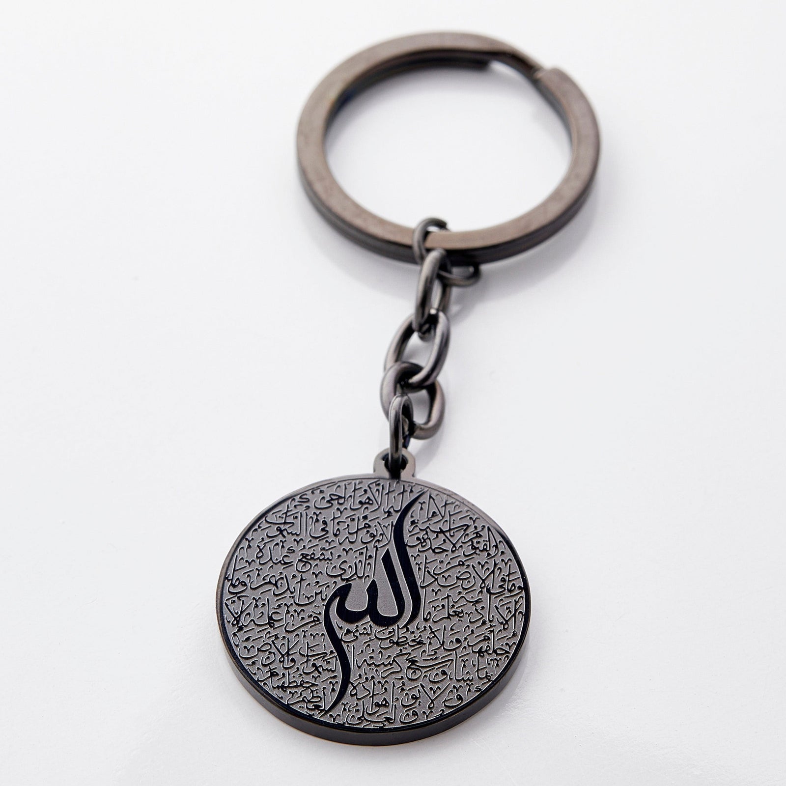 Photo of a black keychain with a round pendant that contains a see-it-to-believe it intricate engraving of the entire verse of Ayatul Kursi