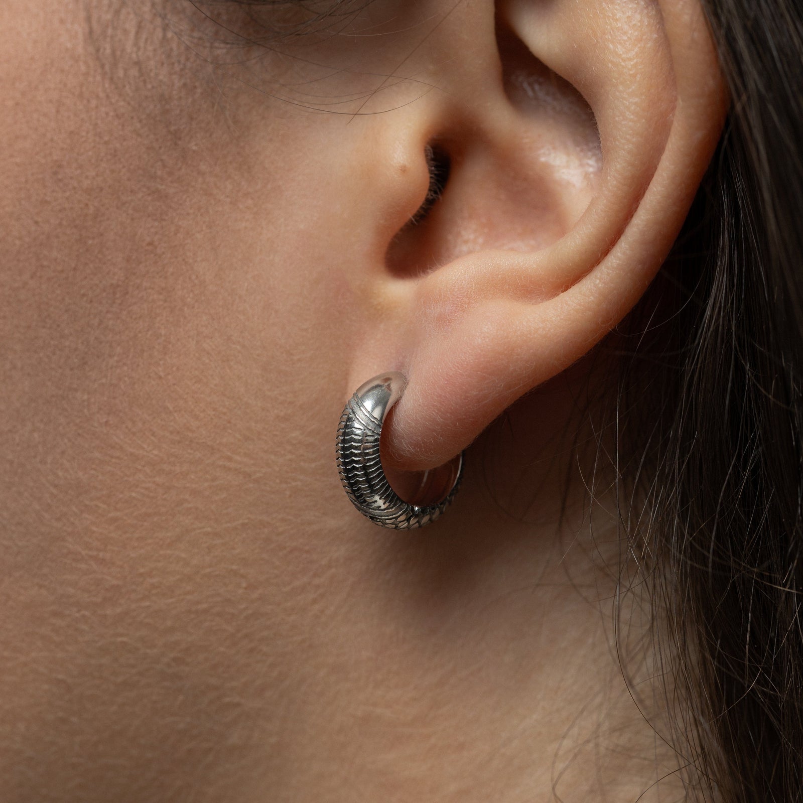 Close-up of an ear wearing a silver keffiyeh mini hoop.