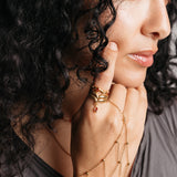 Model styled in 18k gold-plated Nominal jewelry featuring the Keffiyeh Droplet Ring Stack with garnet accents paired with the Red Bead Fishnet Hand Chain.