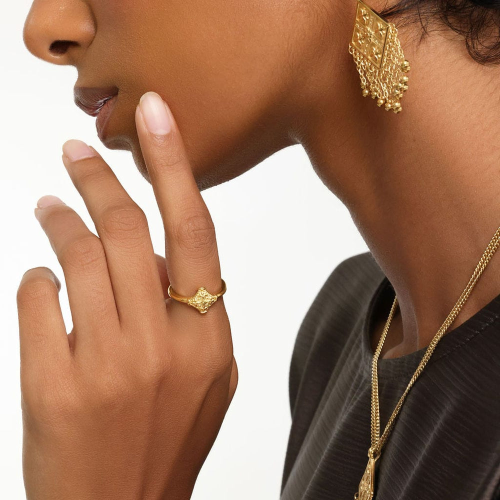 Close up of the model's left hand. The model is wearing the gold Kitework Ring on their left index finger.