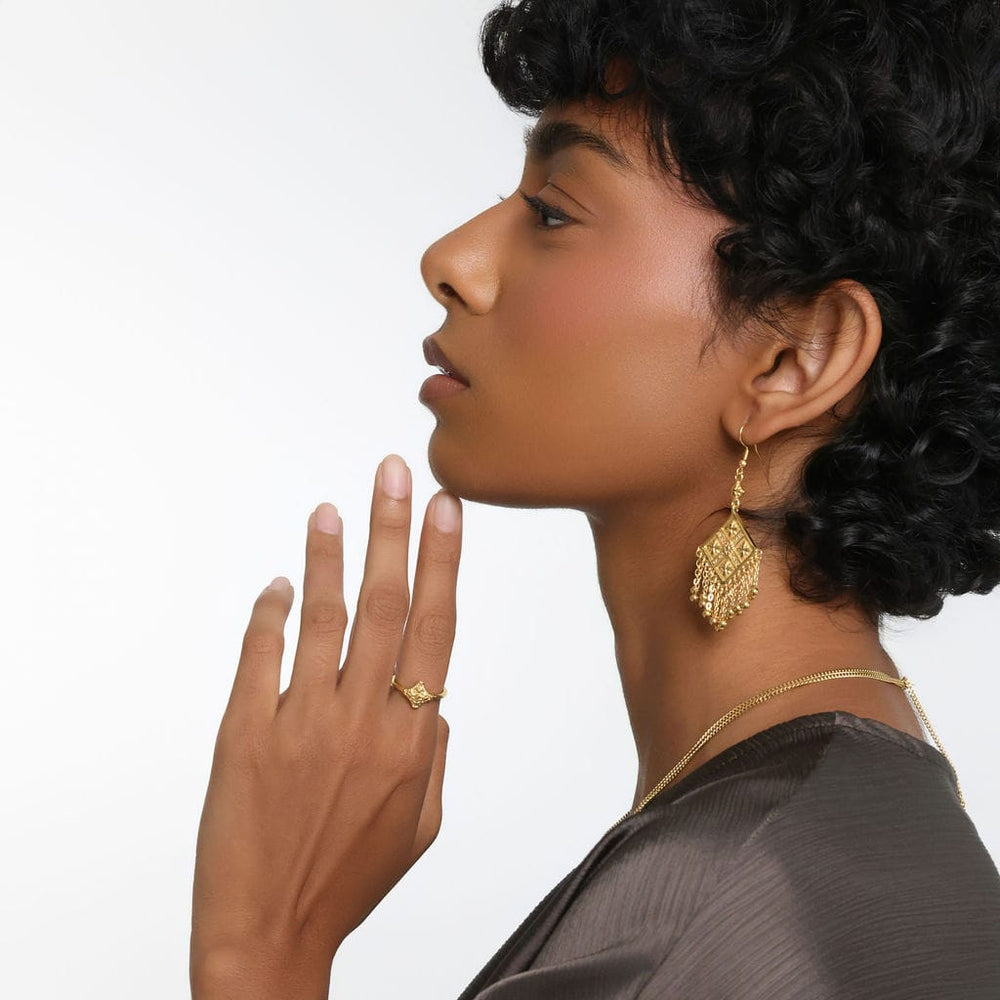 Photo of the model's left side profile with their left hand touching their chin. The model is wearing the gold Kitework Ring on their left index finger. 