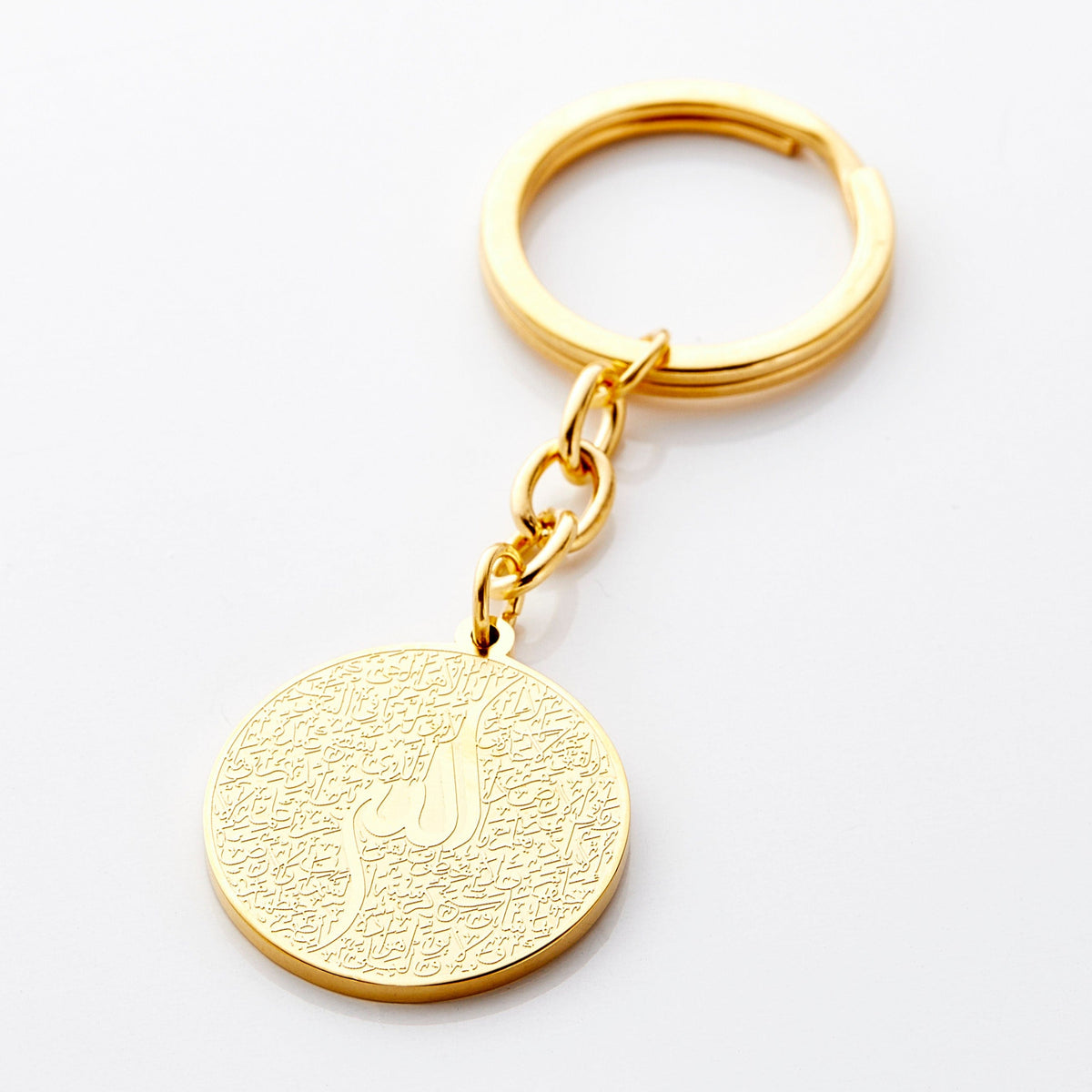 Photo of a gold keychain with a round pendant that contains a see-it-to-believe it intricate engraving of the entire verse of Ayatul Kursi.