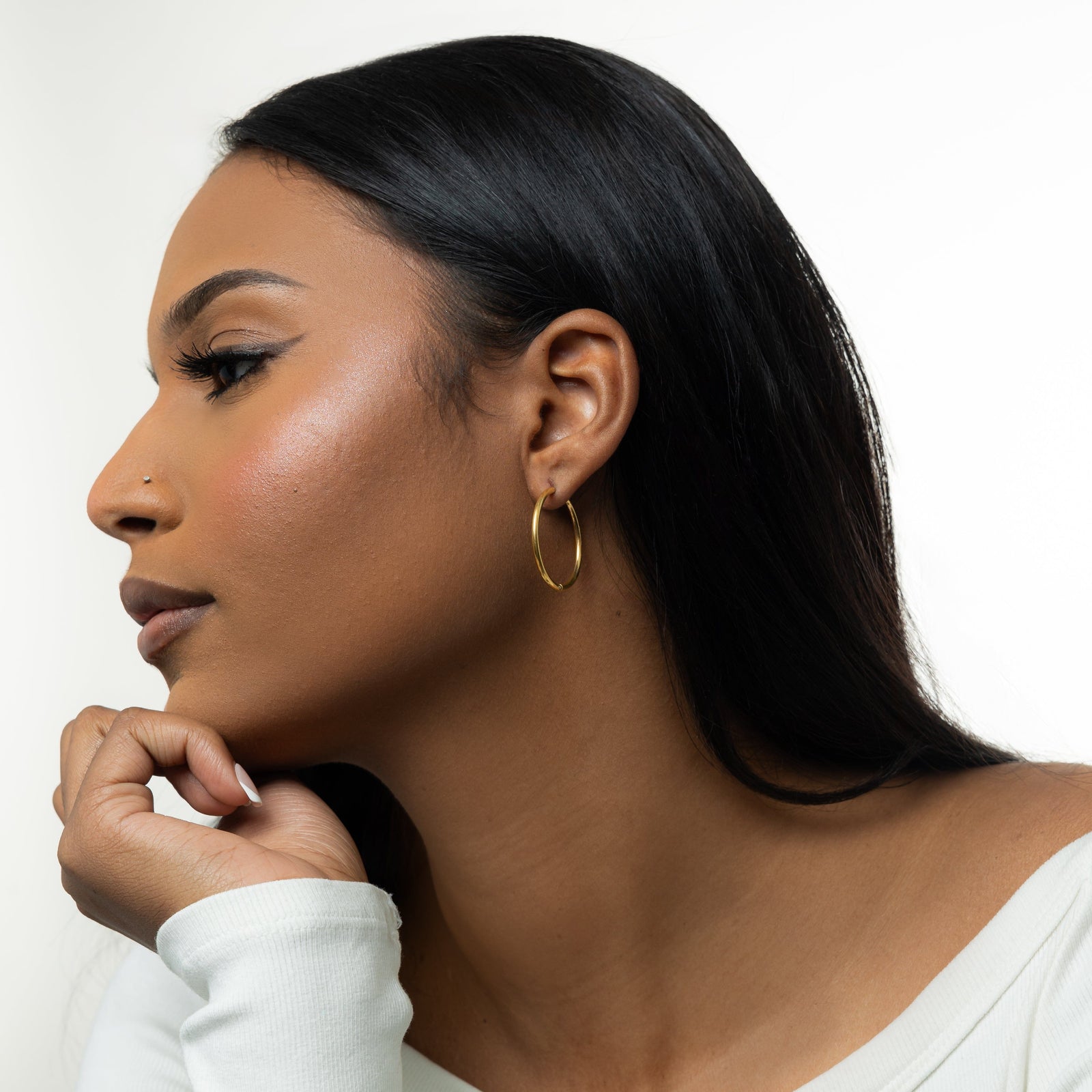 Photo of the left side profile of the model showing the gold Large Essential Hoops | 25mm they are wearing on their left ear.