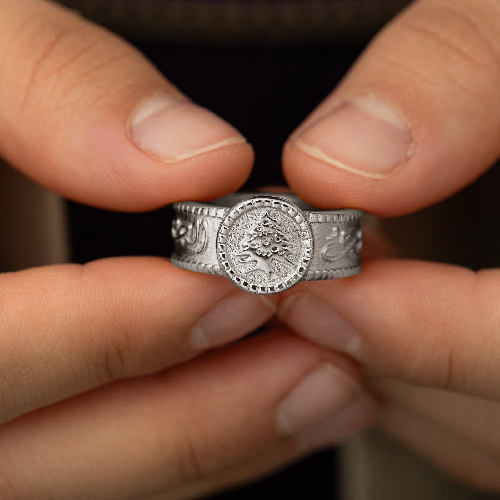 Close up of model holding the silver ring showing the round plate with Cedar of Lebanon design.