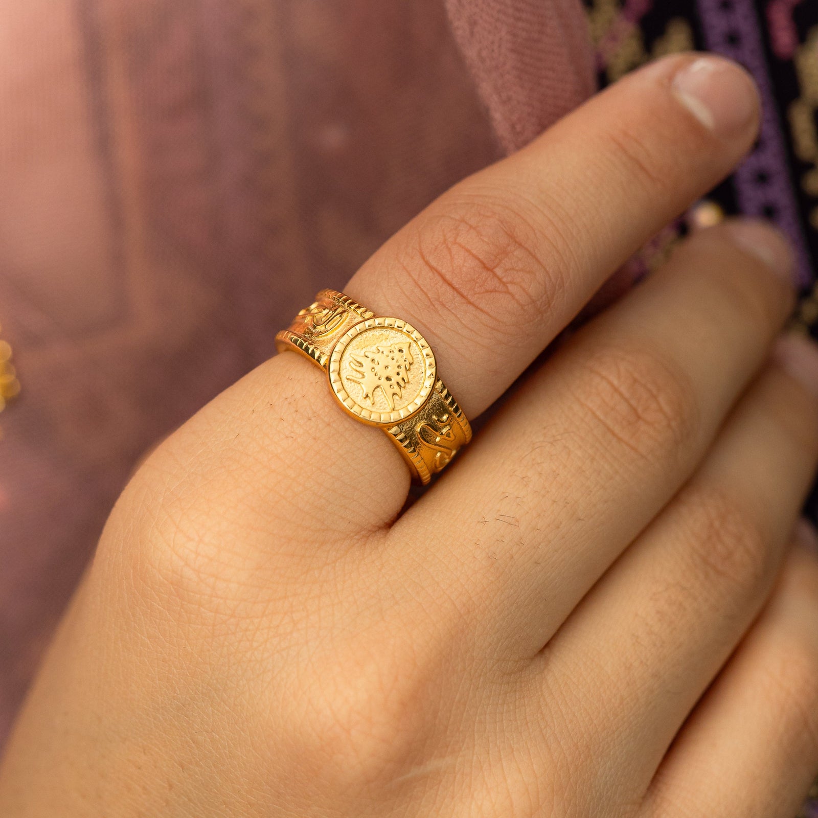 Close up photo of the gold Lebanon Freedom is the Soul ring as worn by the model on their index finger.