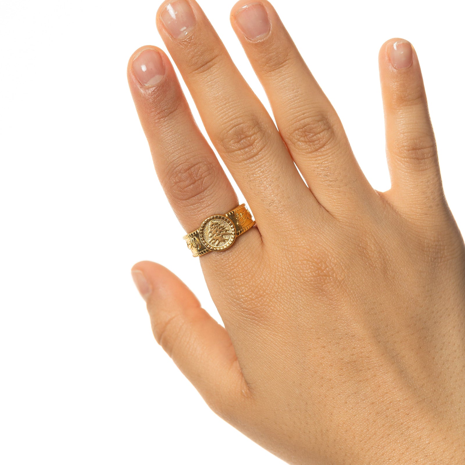 Photo of the hand of a model wearing the gold Lebanon Freedom is the Soul ring on their index finger.