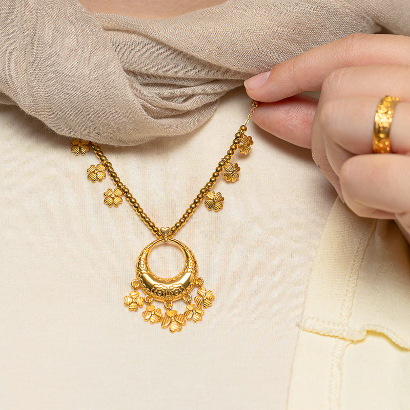Close-up of a hand holding the chain of the gold Levantine Garden Necklace
