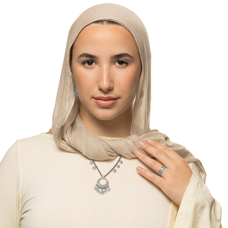 Model wearing the silver Levantine Garden Necklace pimage_ styled over a cream top with a beige hijab. 