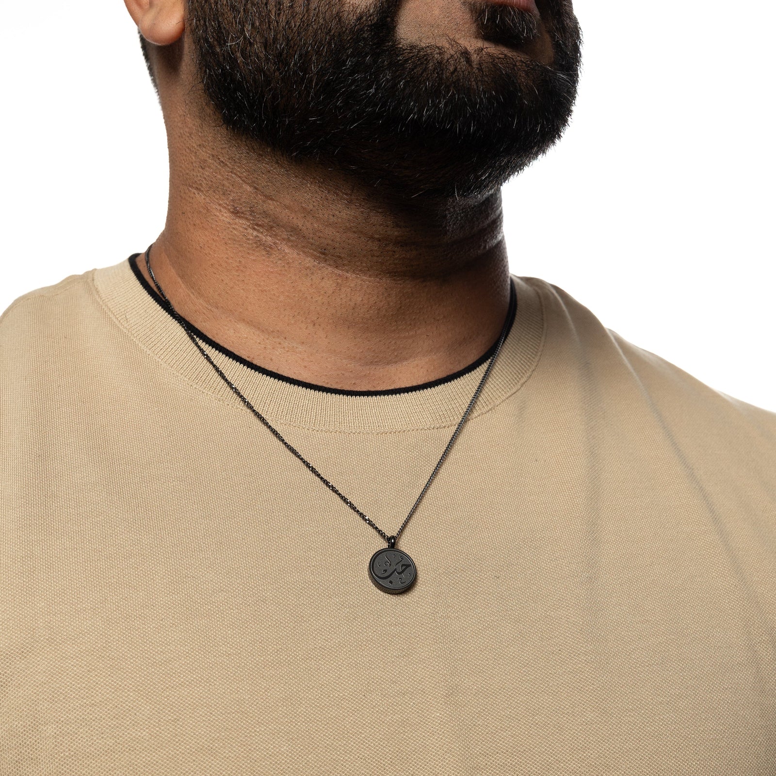 Black Love token necklace worn over a beige shirt
