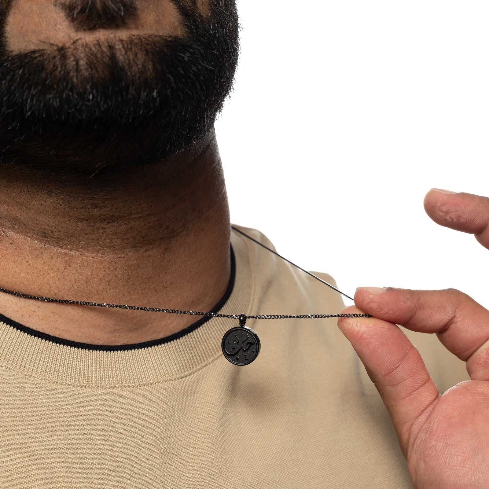 Man holding up a black Love Token necklace while wearing a beige shirt.