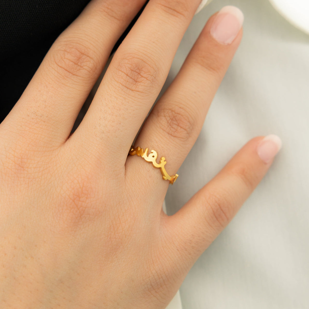 Hand wearing a gold "Love Yourself First" ring on ring finger.
