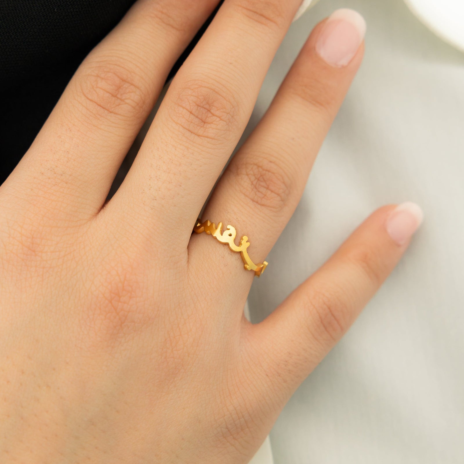Hand wearing a gold "Love Yourself First" ring on ring finger.