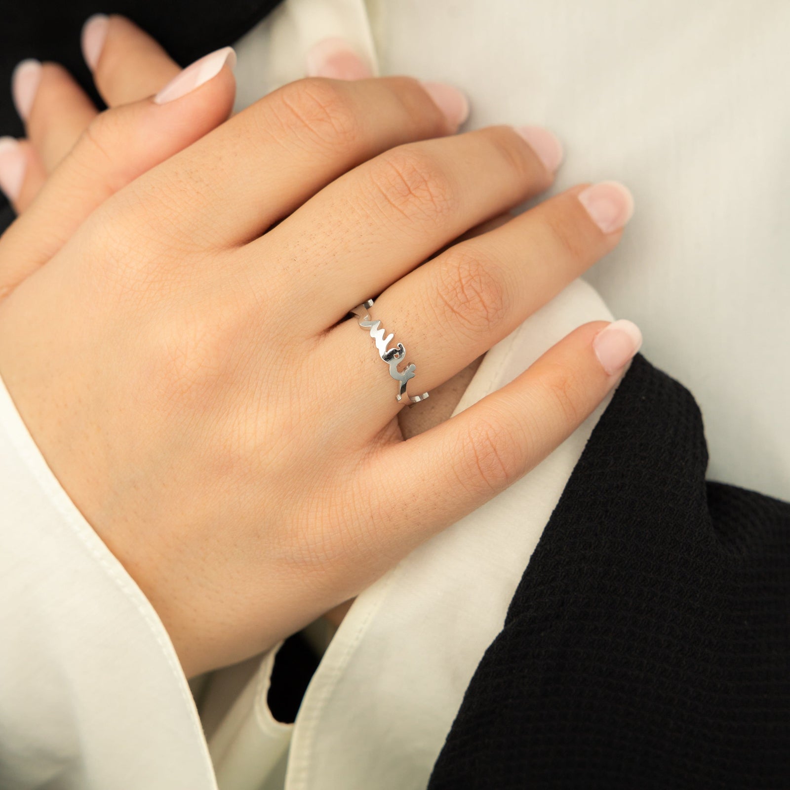 Close-up of a silver "Love Yourself First" Arabic calligraphy ring on the ring finger.