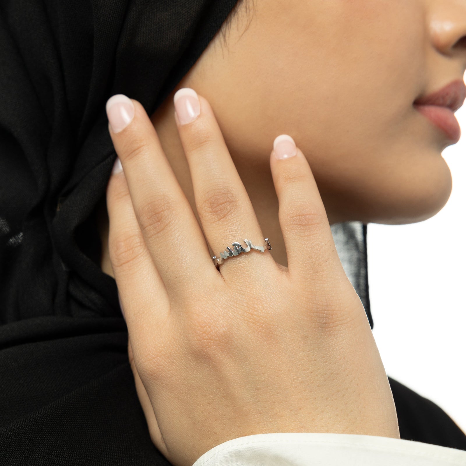 Close-up of a silver "Love Yourself First" Arabic calligraphy ring on the ring finger.