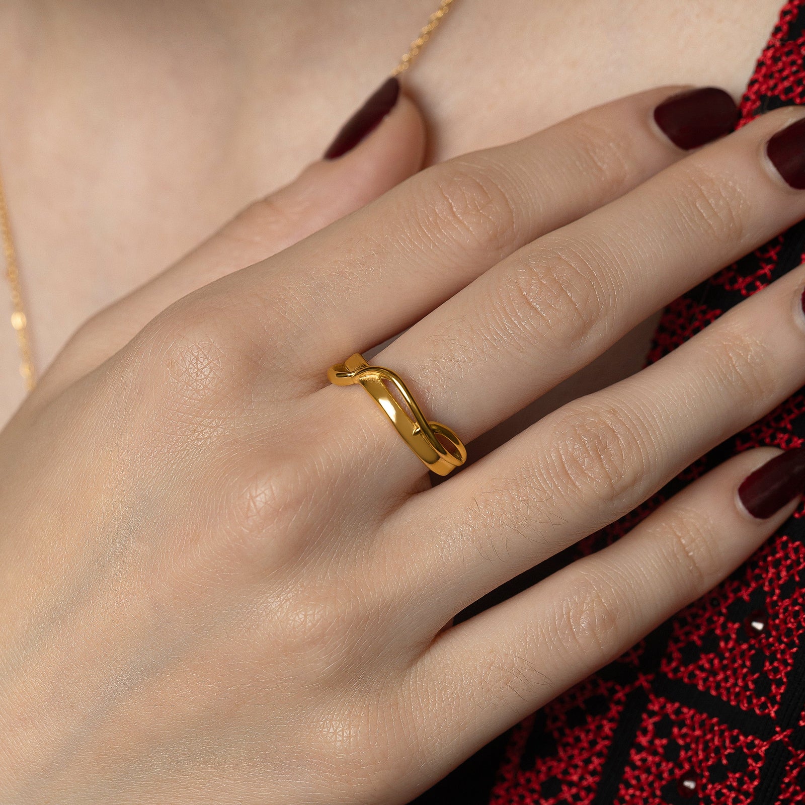 Photo of the model's right hand, gold Love | حب Intertwined Ring on their right middle finger.