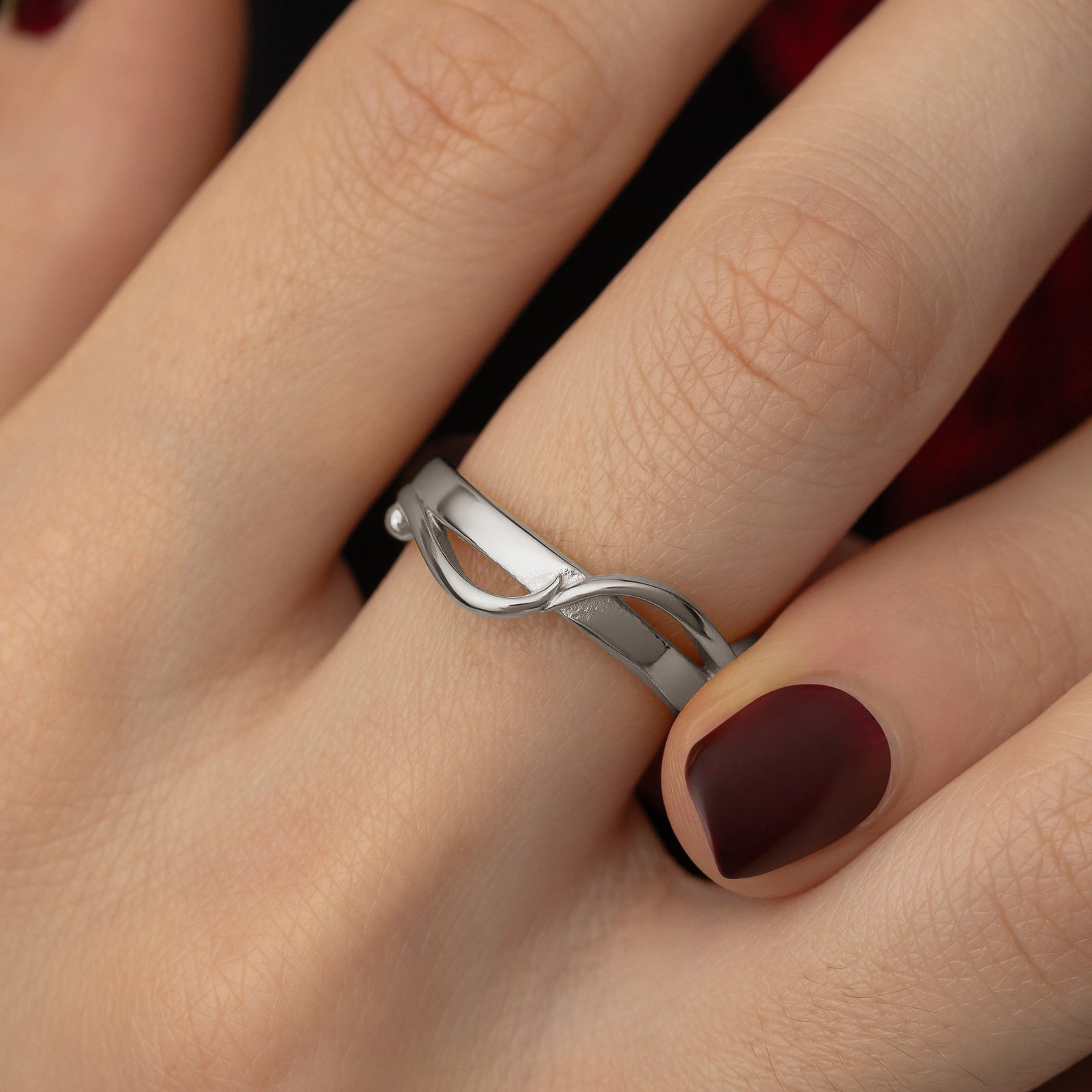 Close up photo of the silver Love | حب Intertwined Ring worn by the model.