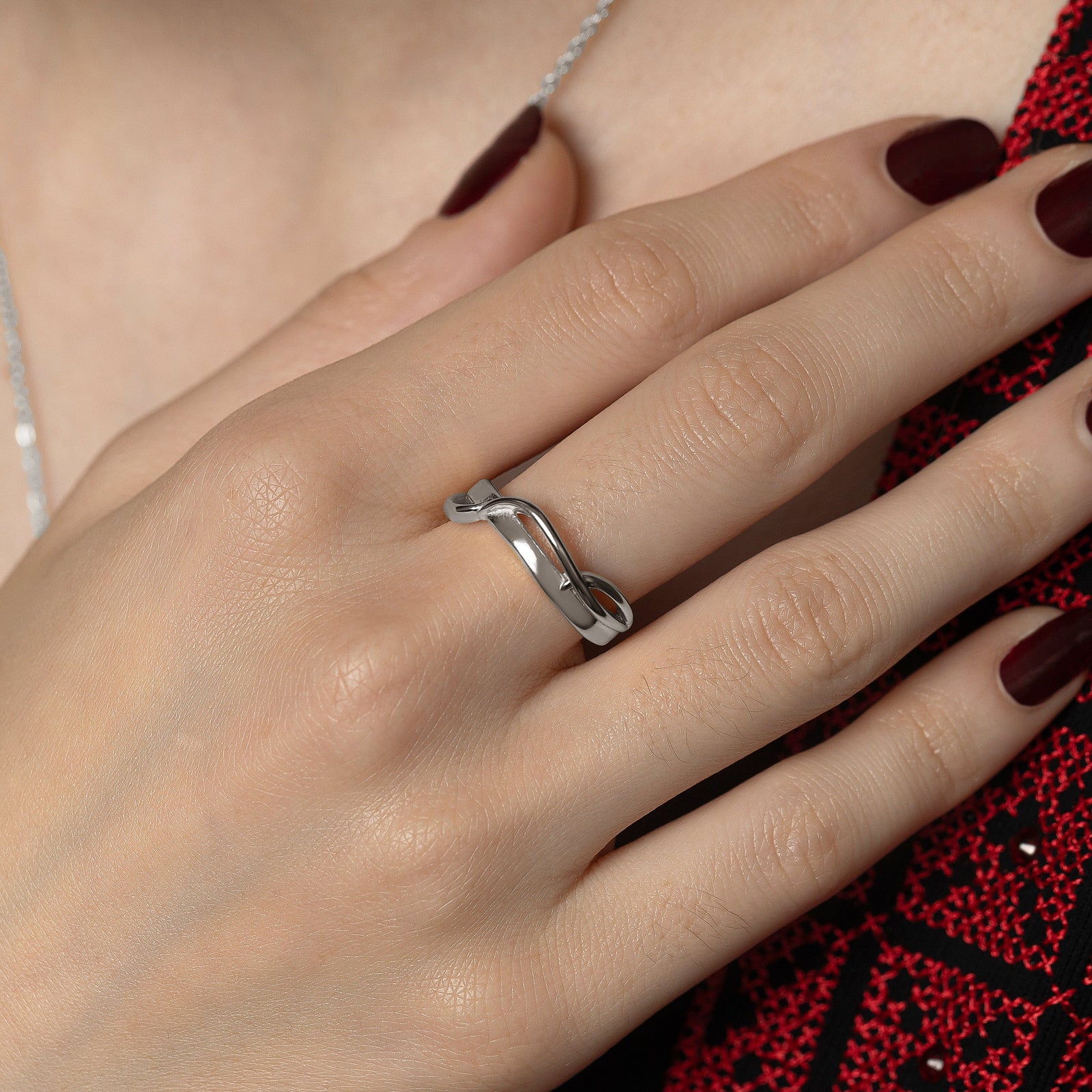 Photo of the model's right hand, silver Love | حب Intertwined Ring on their right middle finger.