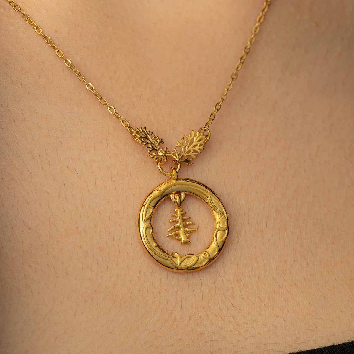 Close up photo of the Love of the Homeland Lebanon Cedar gold pendant as worn by a model