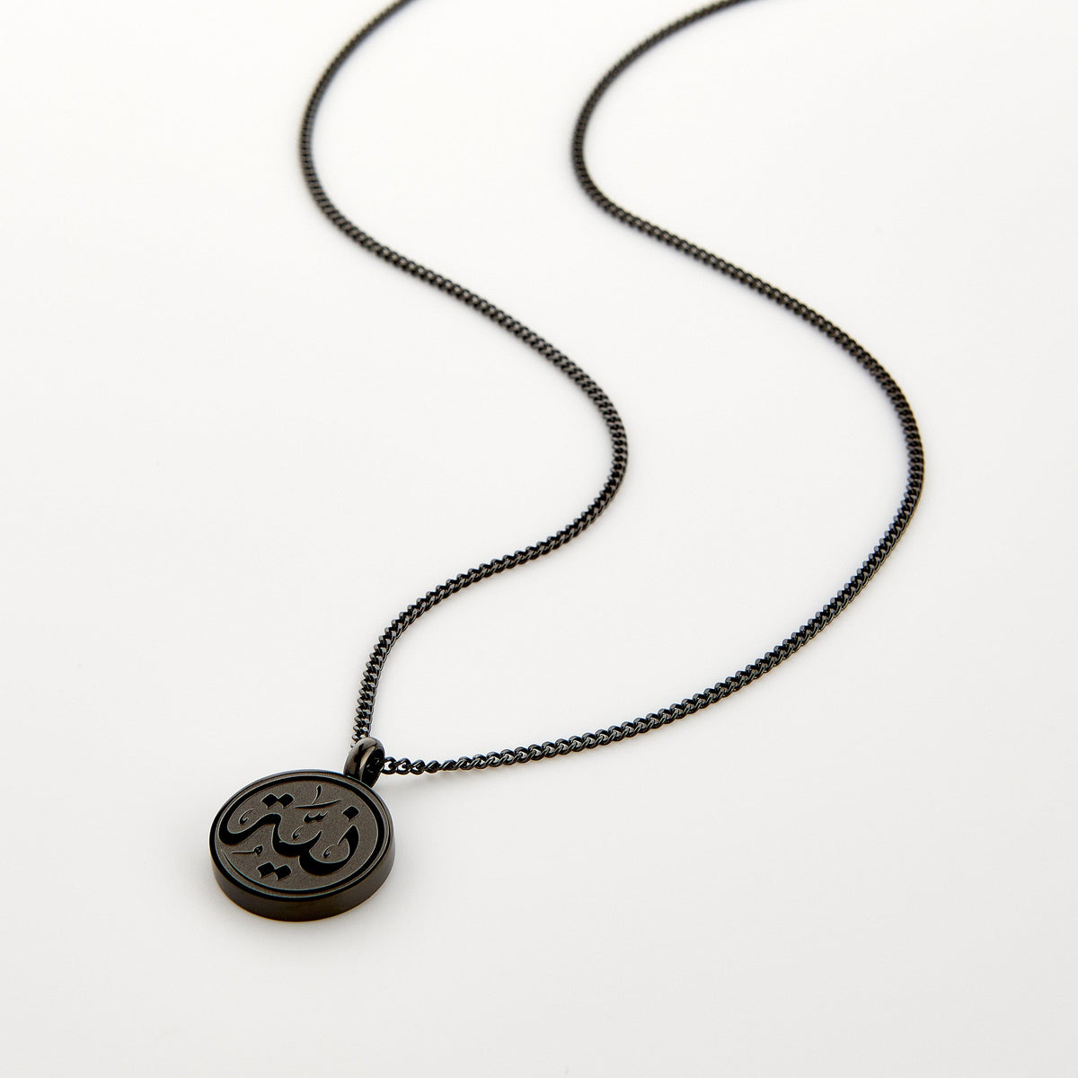 Black necklace with a circular pendant engraved with 'Niyyah' calligraphy, displayed on a white background.